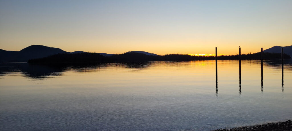 Sunset over calm water with silhouetted mountain ridges near Prince of Wales Island