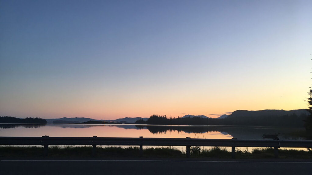 Twilight over a calm island waterway with silhouetted hills